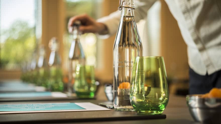 Close-up of man putting cap on glass water bottle in row of bottles, green glasses, meeting agendas