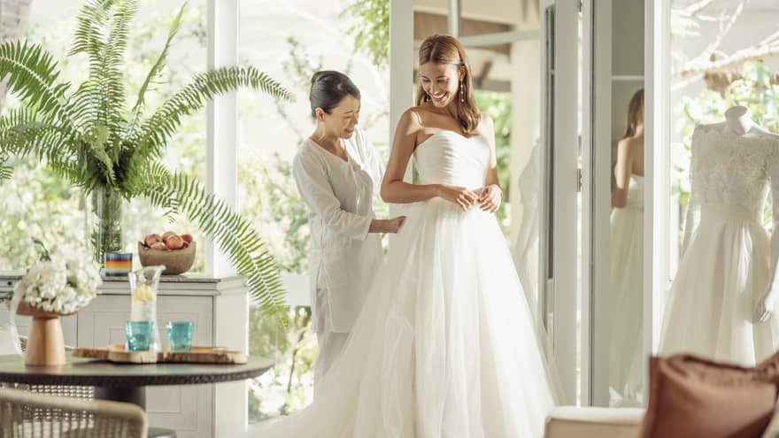 Wedding tailor helps bride in her wedding dress