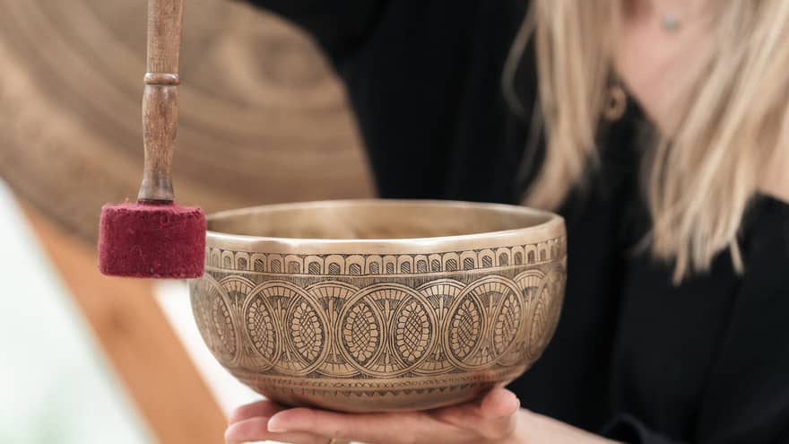 Person holding a gold engraved sound bath healing bowl