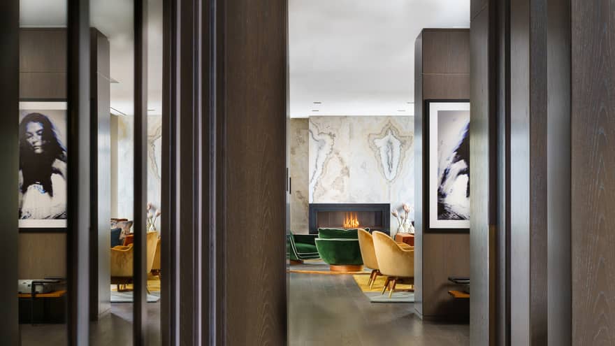 Entryway to suite, dark wood floors, mustard- and emerald green-coloured arm chairs by fireplace