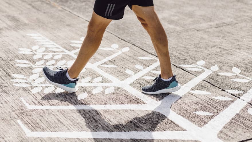 Man in navy blue trainers walks across Four Seasons logo on runway