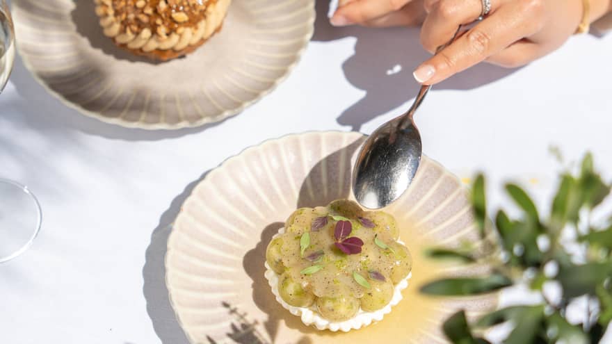 Two people partake of elegant desserts on artistic scallop-edged plates.
