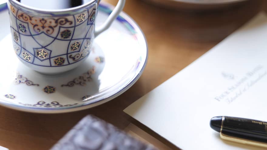 Close-up of decorative tea cup, top of pen on Four Seasons letterhead