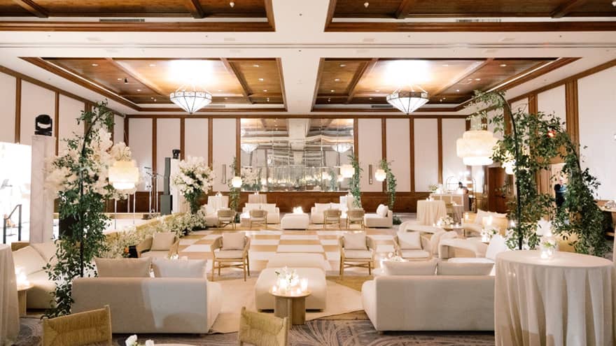 A wedding venue with couches and chairs and flower bouquets on the tables