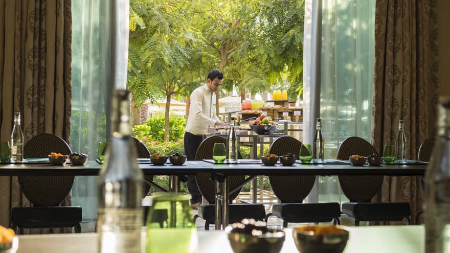 Hotel staff sets patio table with coffee service outside Jawhara Meeting Room