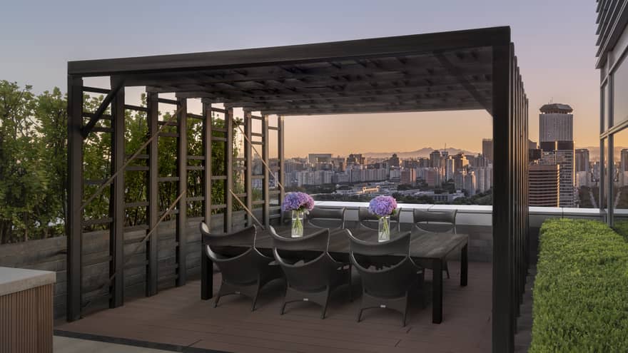 Outdoor city rooftop terrace, with dining table under a pergola