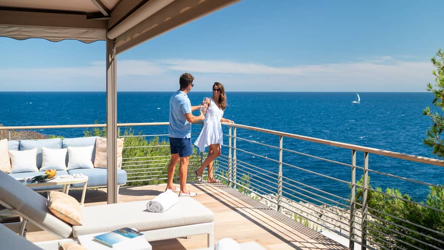 Couple in corner of Club Dauphin patio overlooking blue sea, skies