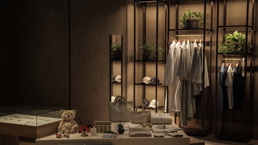 Spa boutique with shelf of white robes and shirts hanging along with other retail items