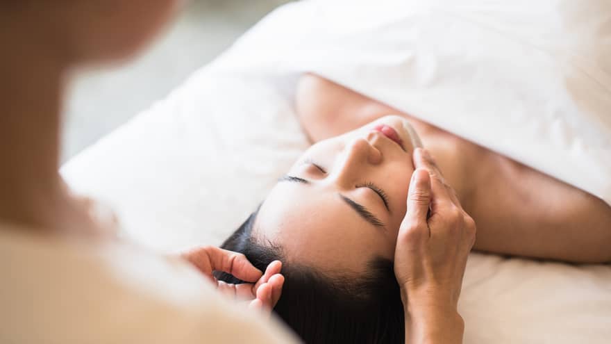 A guest receiving a soothing facial at a spa, lying on a massage table, surrounded by calming décor and soft lighting.