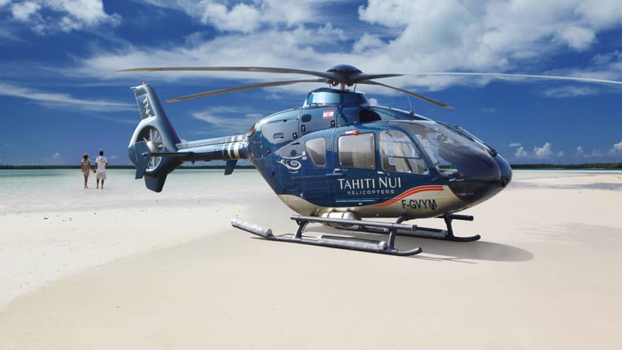 Guests walk on the beach before boarding the Tahiti Nui Helicopter for an island tour
