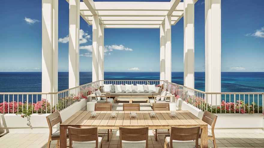 Penthouse Suite large patio dining table, seating area under white pergola, blue sky