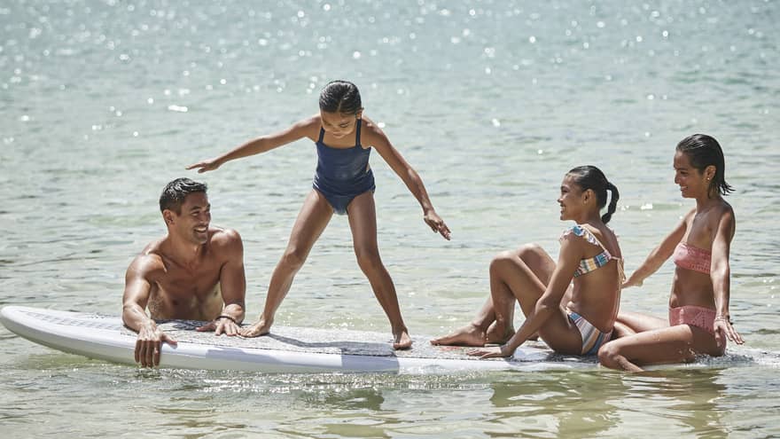 A family sitting on a large surf or paddleboard.