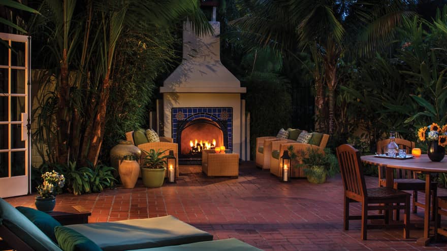 Fremont Bungalow tile patio with large stone outdoor fireplace, chairs, lounge chairs, dining table