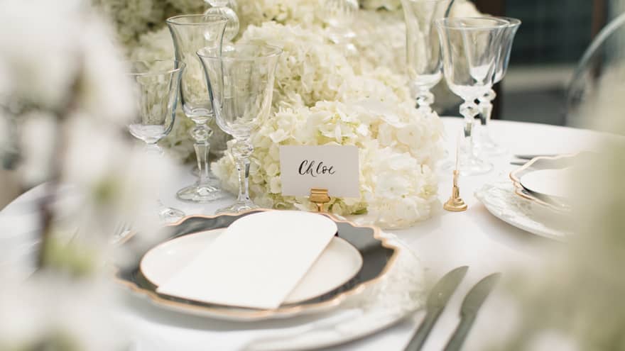 Close-up of wedding place setting with white flowers on table