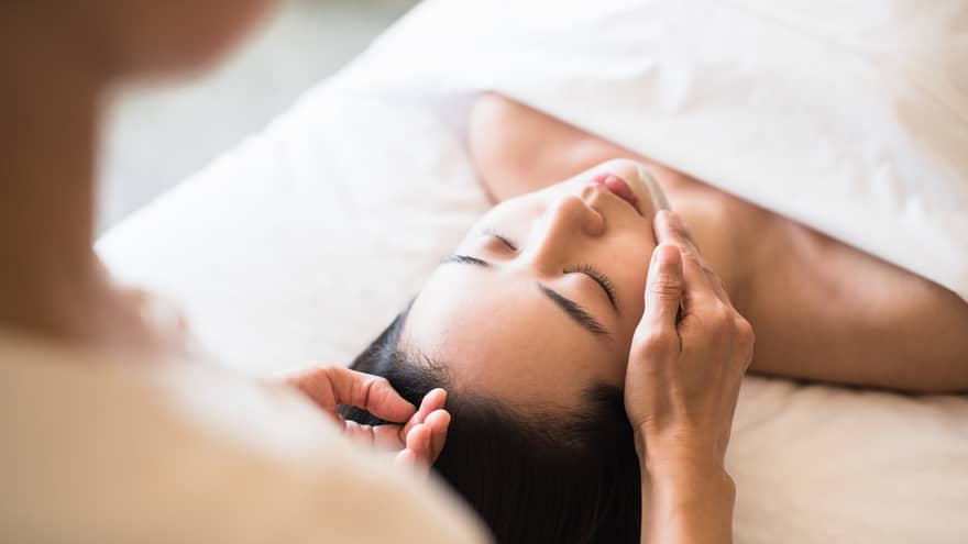 A guest receiving a soothing facial at a spa, lying on a massage table, surrounded by calming décor and soft lighting.