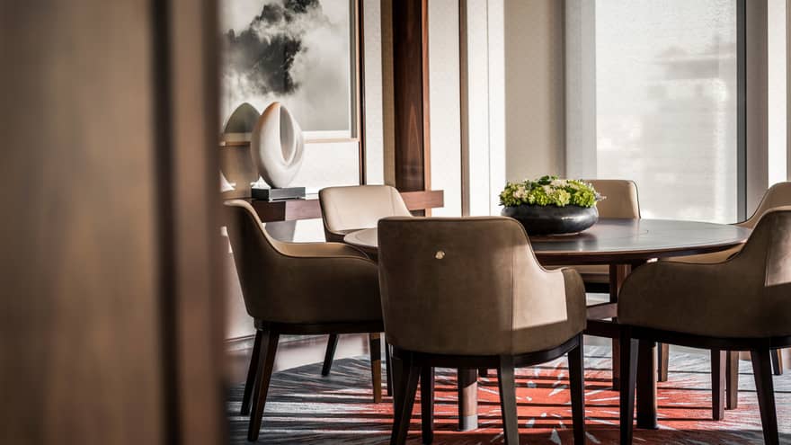 Leather dining chairs around round table with flowers, console table with white sculpture under painting