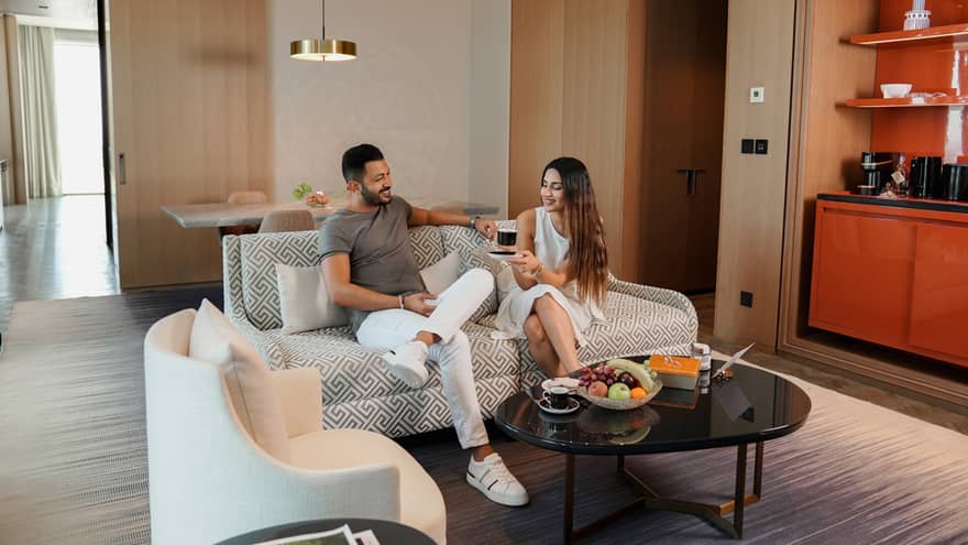 Man and woman sit on sofa in hotel suite