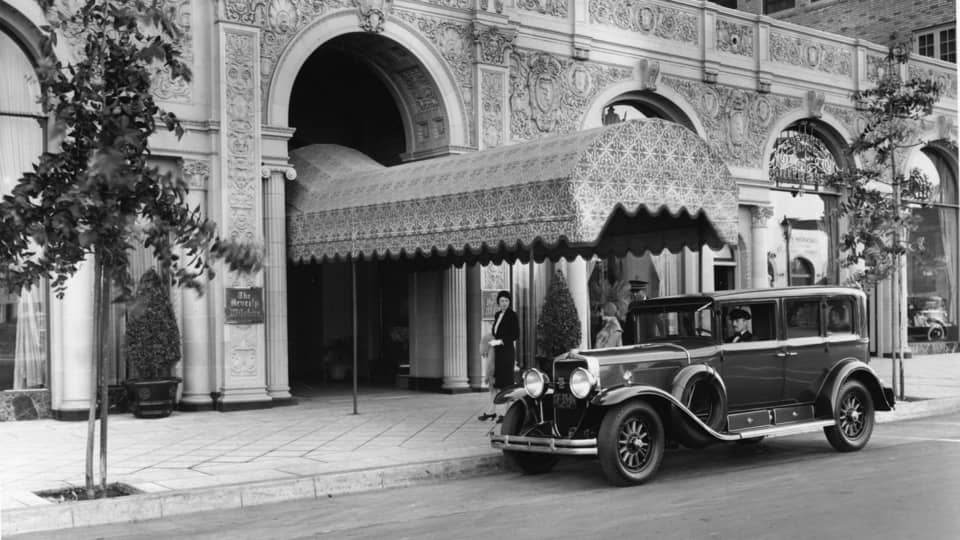 Historic photo of Beverly Wilshire entrance with car parked in front