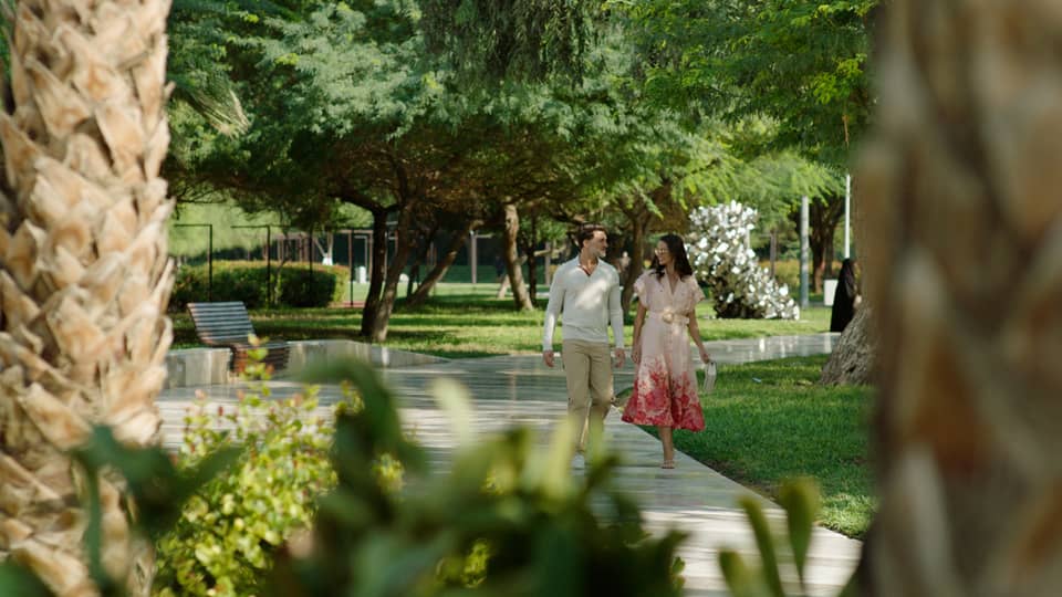 Couple walks along pathway surrounded by flora and fauna