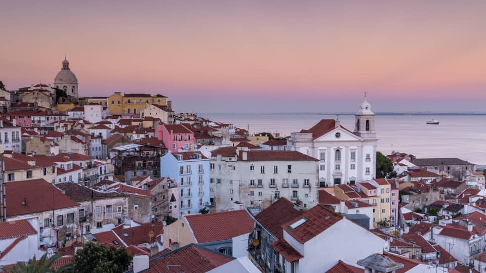 Aerial view of Lisbon traditional buildings with white houses, apartment buildings with brown roofs, white church