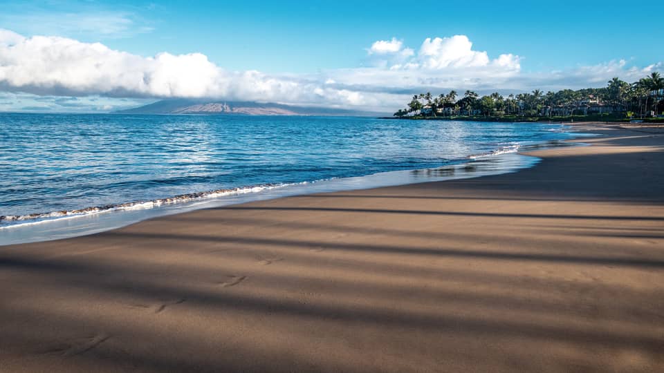 A beach shore with blue waters and a bright sky.
