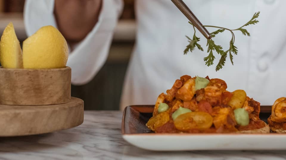 A chef picking up an herb with a utensil.