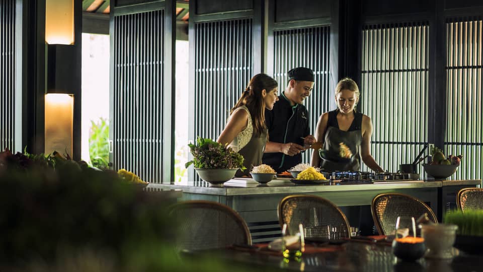 Chef, two women look at pan on kitchen range at Hoi An Cooking Academy