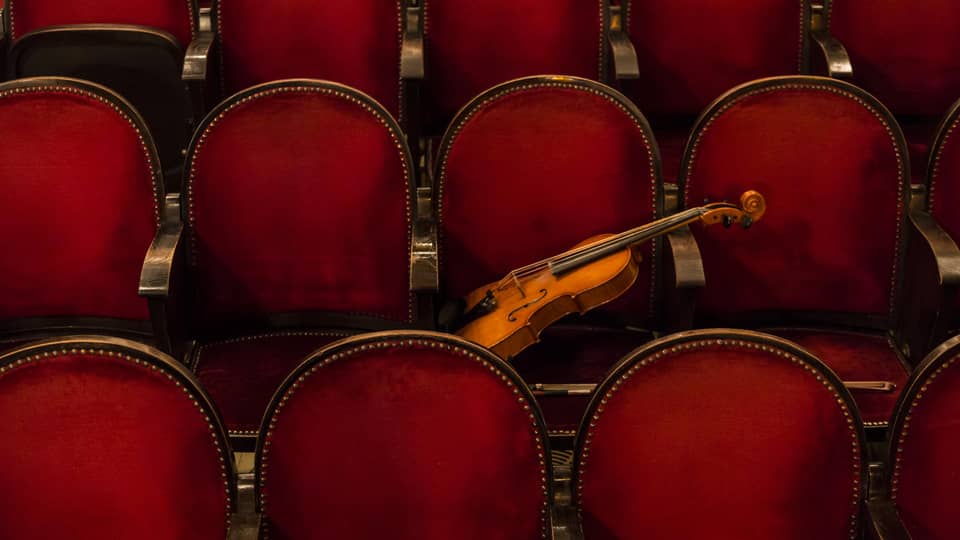 Red theatre chairs with a violin resting on one.