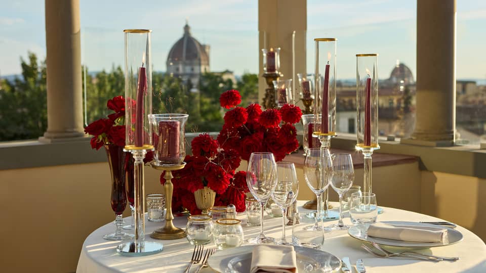 Terrace with elegant, romantic table set for two with crystal glassware and candlesticks looking out to the Duomo