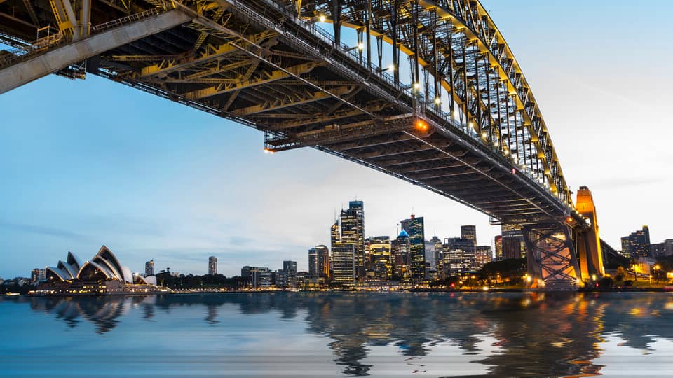 View from under bridge to Sydney waterfront skyline, lights at dusk