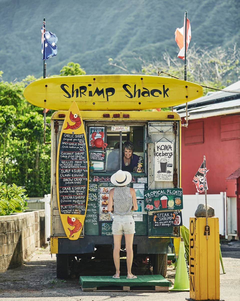 Woman orders from Shrimp Shack food stand with colourful yellow signs