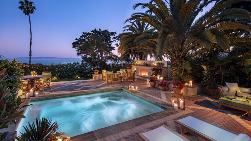Illuminated villa plunge pool and patio, palm trees at dusk