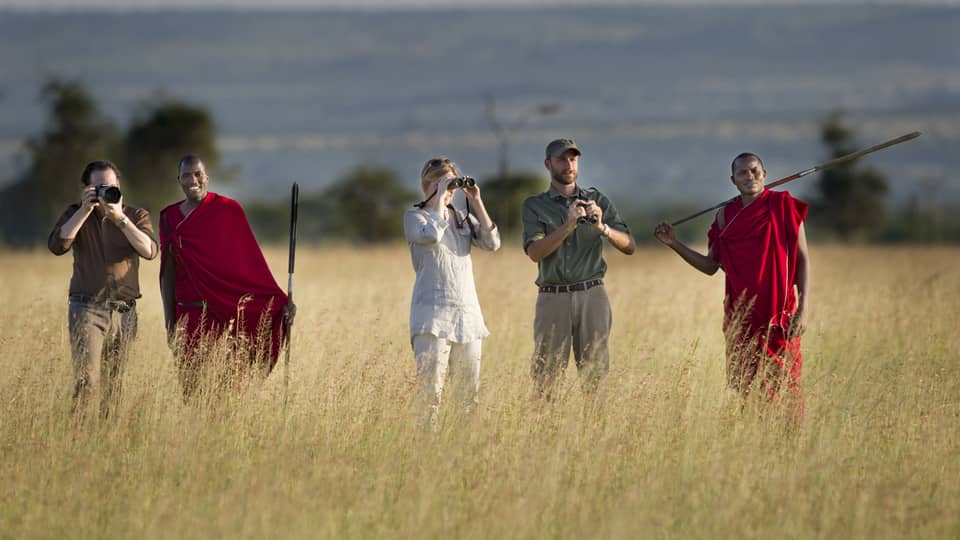 Couple takes photos on walking safari through tall grass with guides