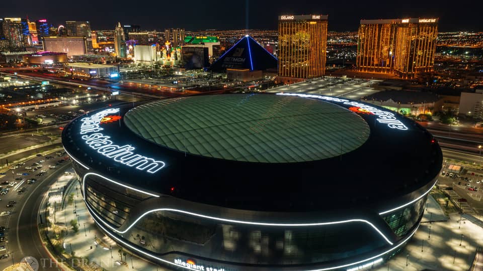 A nighttime, birds-eye view of a large sports stadium, with other tall buildings and lights around it.