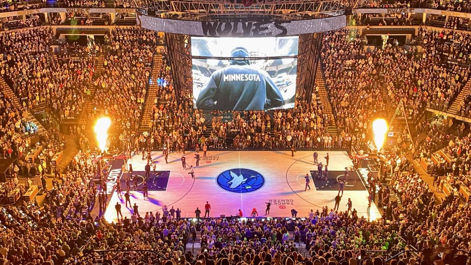 Large audience watching a basketball game with purple lights on the basketball court.