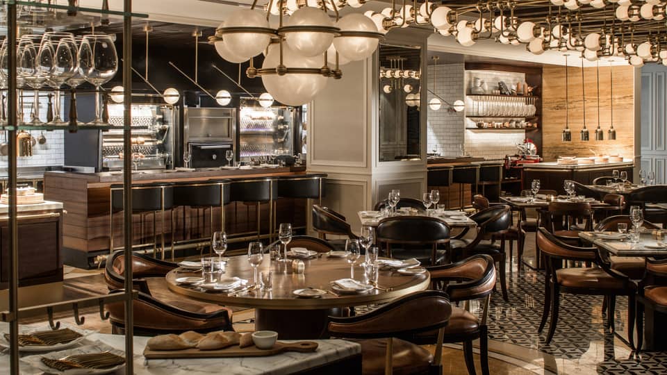 The interior of a dining outlet with many hanging lights, various tables, and a bar.