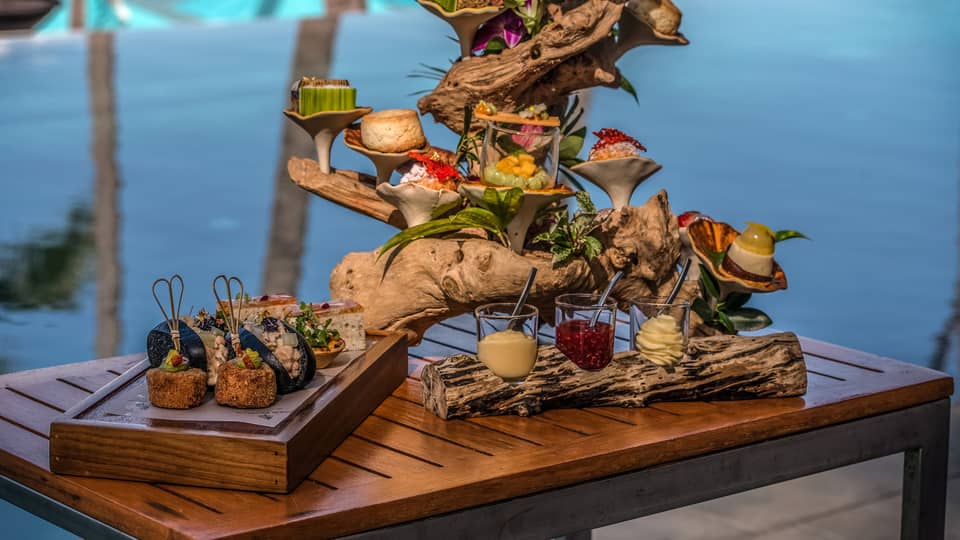 Afternoon tea spread with sweets and savouries presented on a piece of driftwood