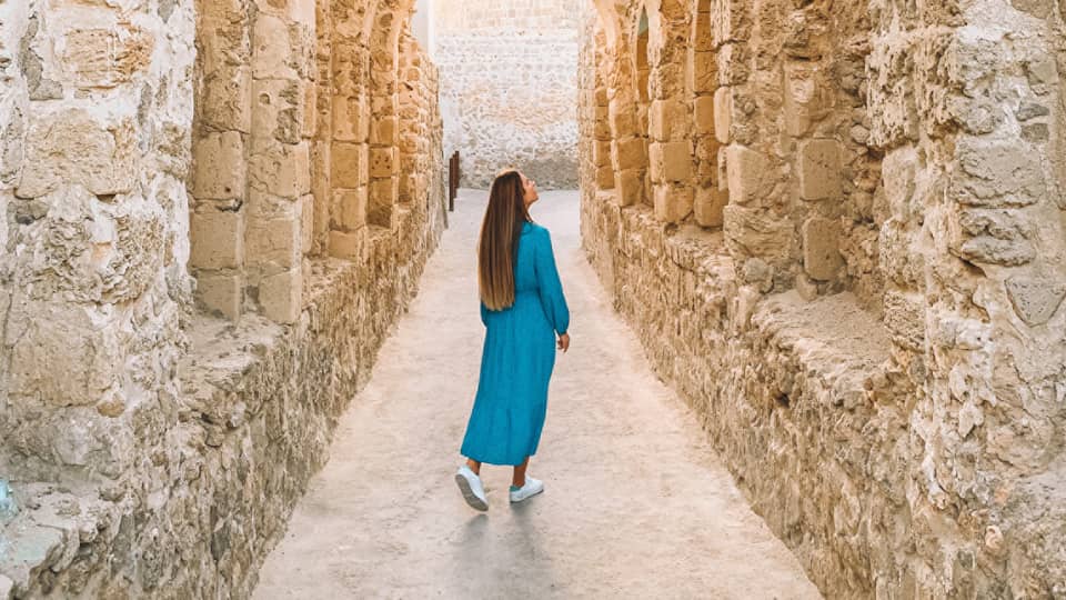 A woman stands underneath a stone pathway.