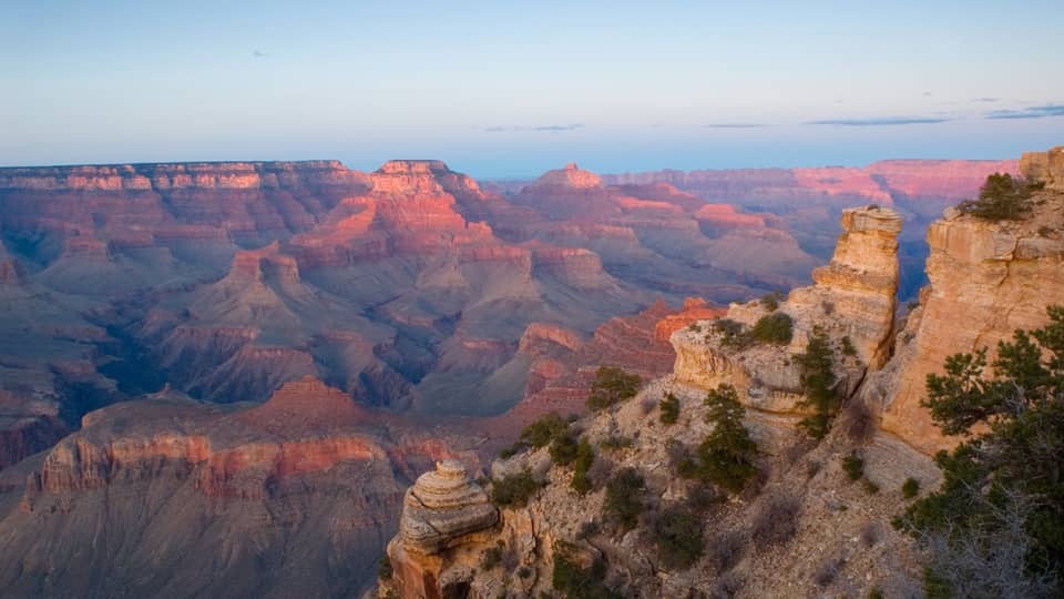 Sweeping view of Grand Canyon cliffs, canyon ridges, pink light from sunset