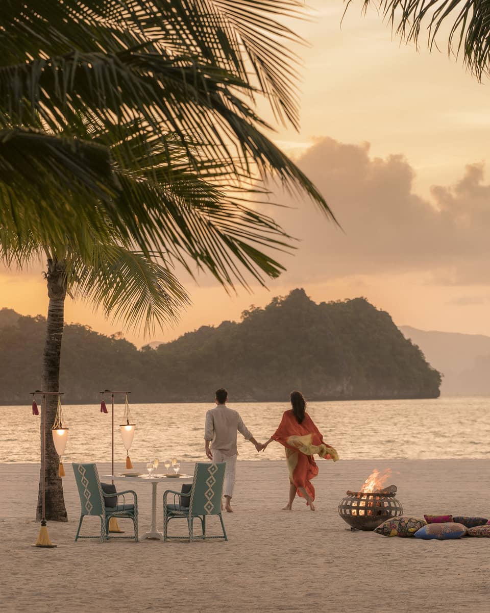 A man and woman on a beach having a Punta chintai private dinner at Four Seasons Langkawi