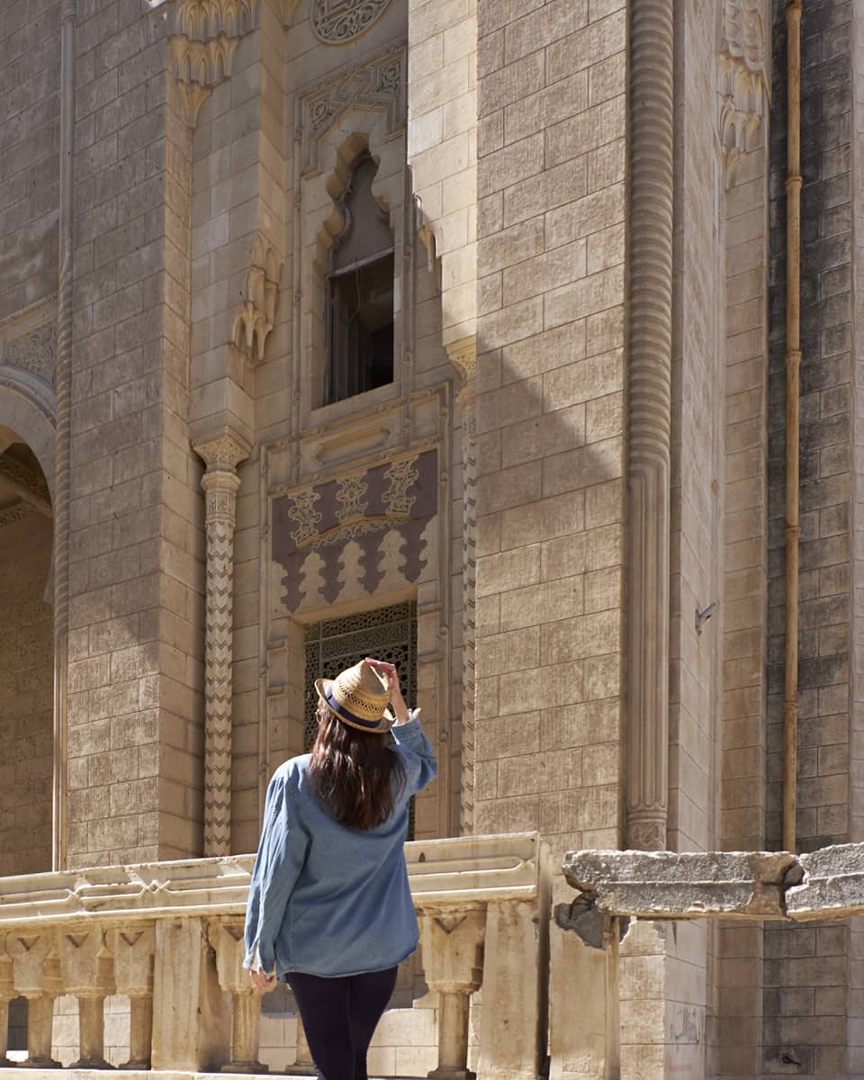 Woman looks up at historic palace exterior in Alexandria, Egypt
