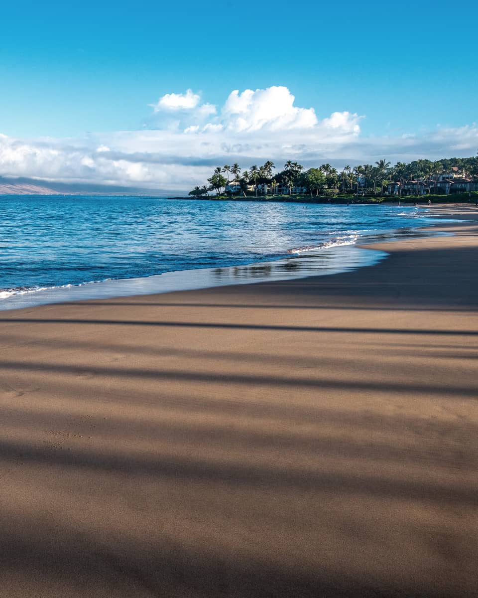 A beach shore with blue waters and a bright sky.