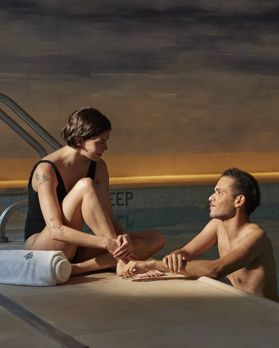 Person sitting poolside with a towel talking to another person leaning on the edge of the pool at Four Seasons luxury hotel