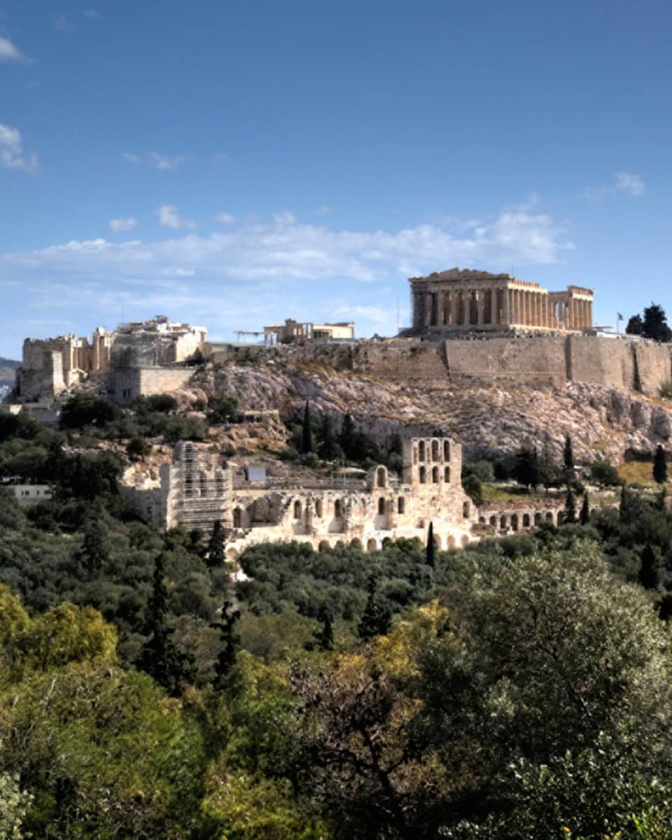 Ancient ruins of Acropolis on mountain surrounded by greenery