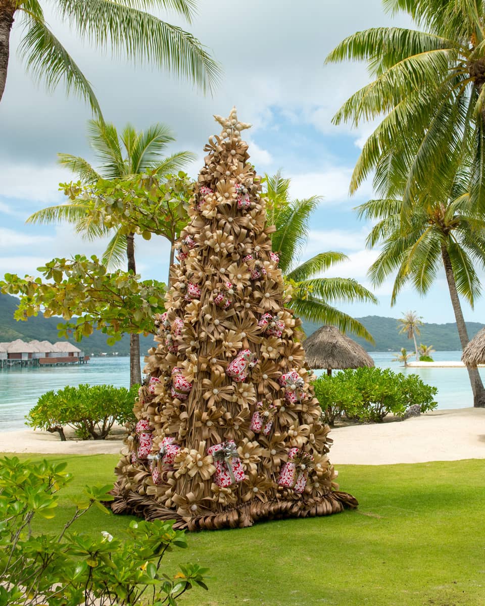 Decorative Christmas tree on resort lawn surrounded by palm trees