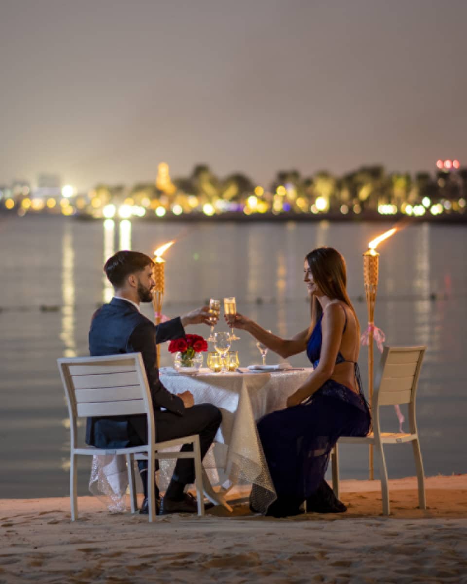 A couple dines along the gulf with the Doha city skyline in the background.