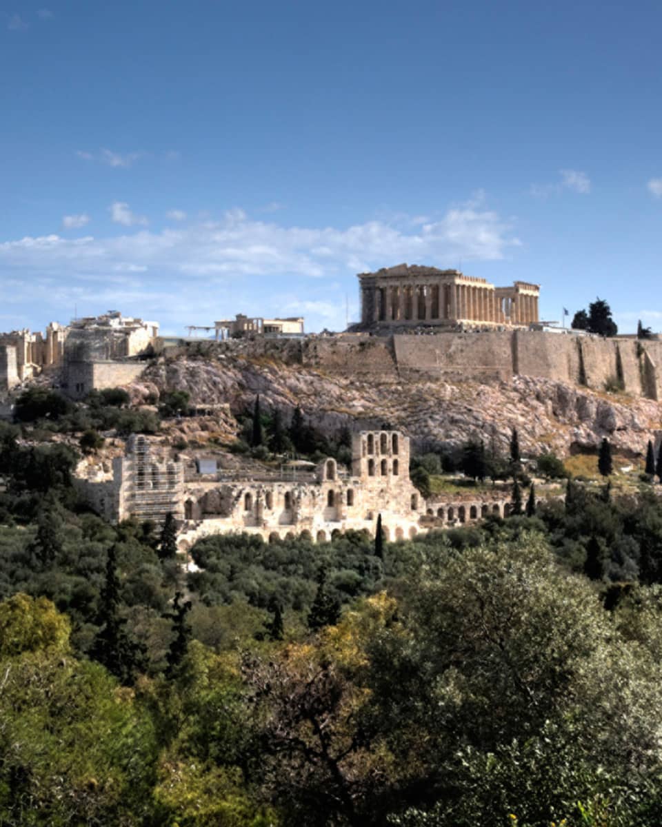 Ancient ruins of Acropolis on mountain surrounded by greenery