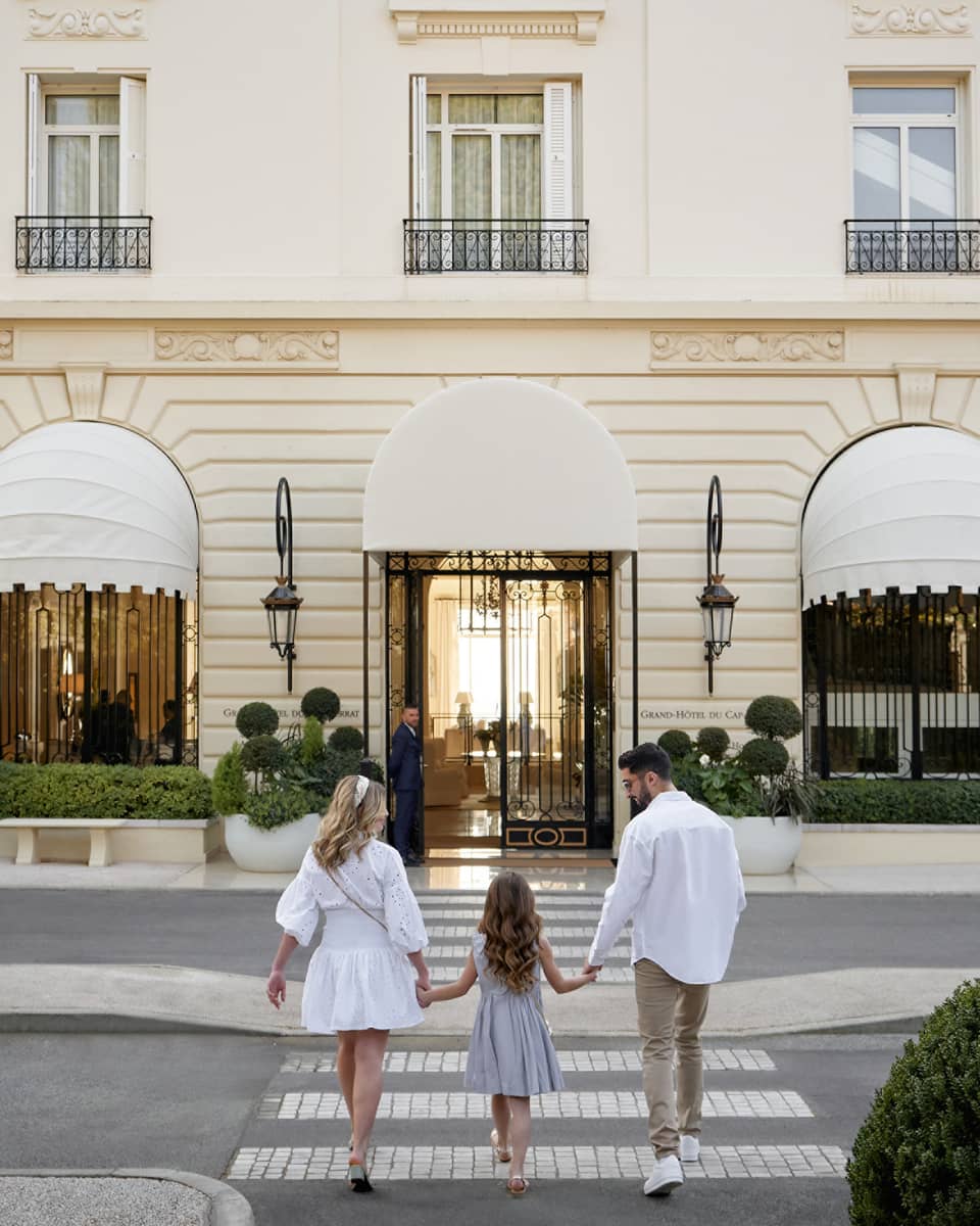 Family of three holding hands while walking toward the Grand-H�tel