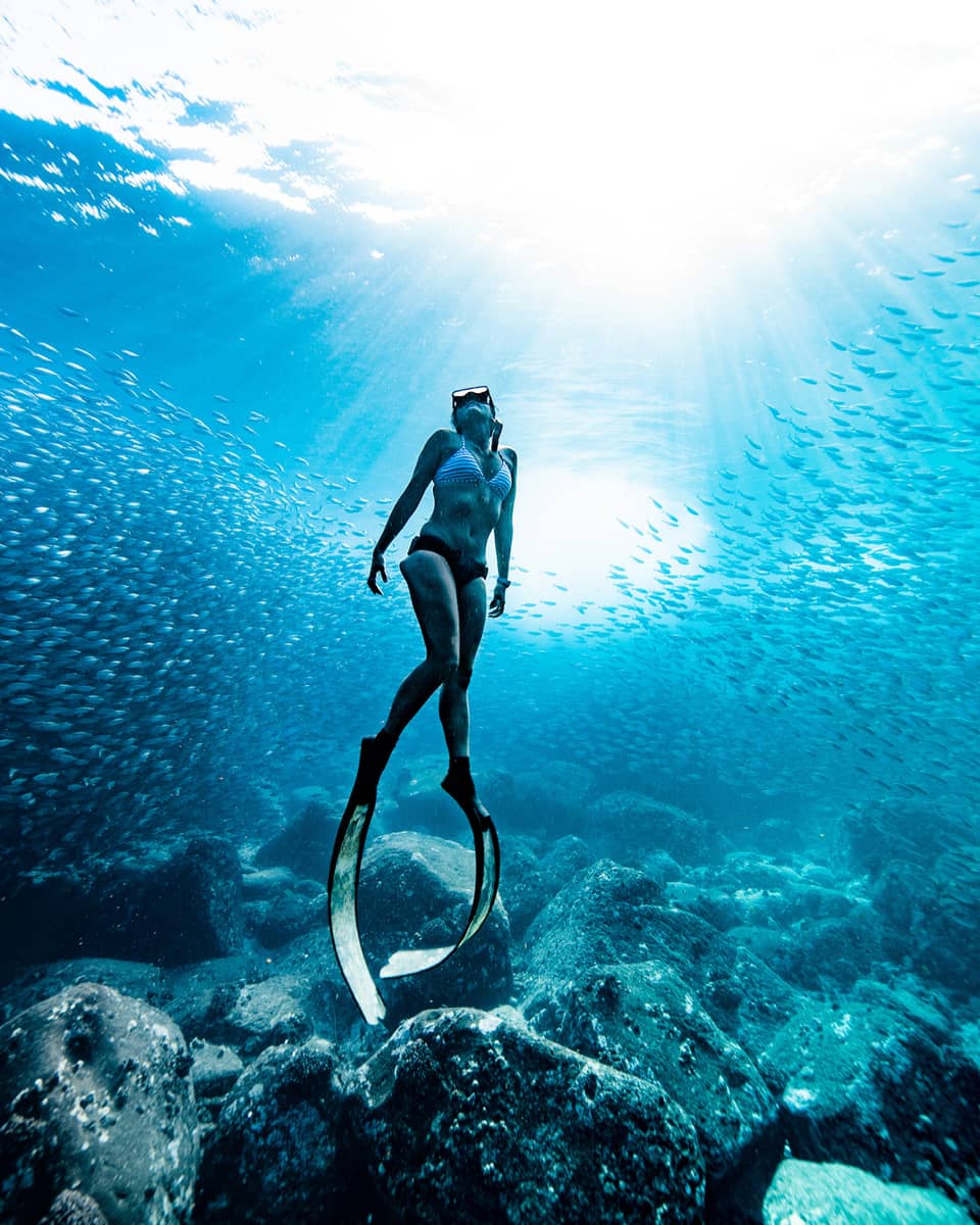 A woman in bikini wears scuba slippers below the surface of the ocean water