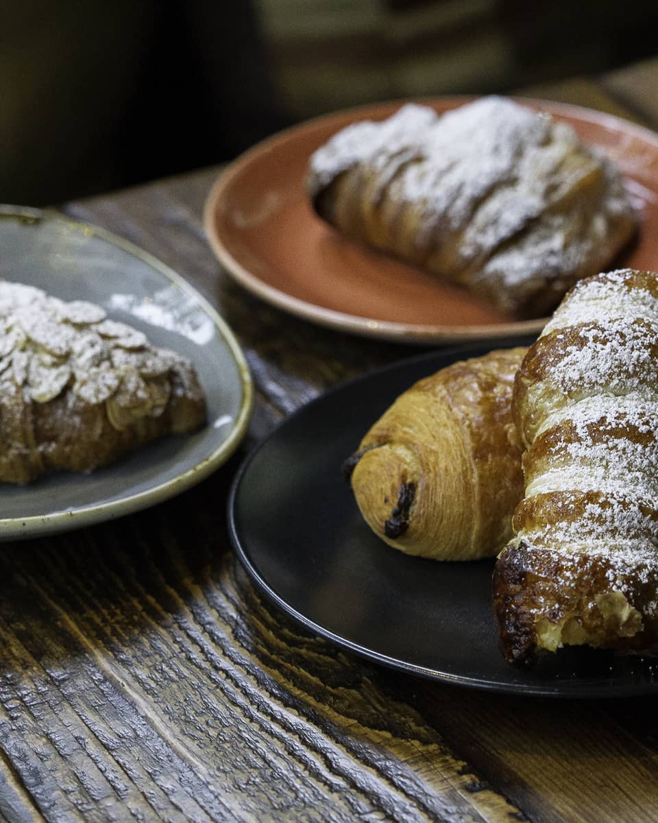 Four different croissants and pastries on a black, grey, and orange plate.